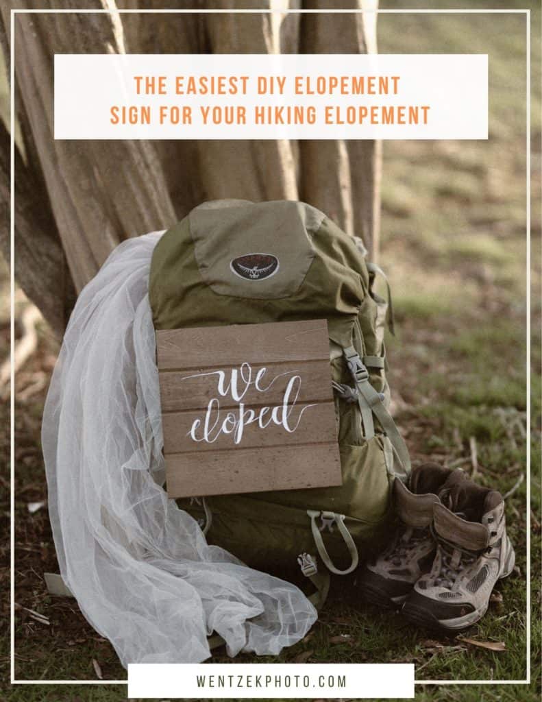 DIY we eloped sign hanging on a hiking backpack with a wedding dress and hiking boots on the sides. 