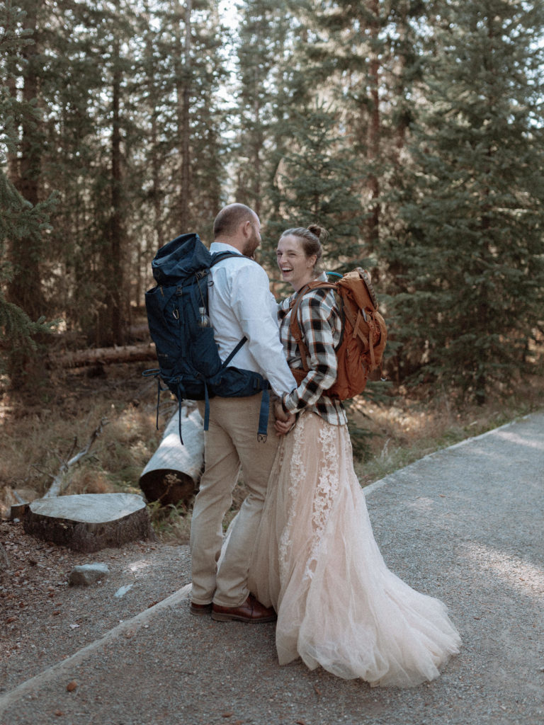 Couple in wedding attire and backpacks for their elopement. 
