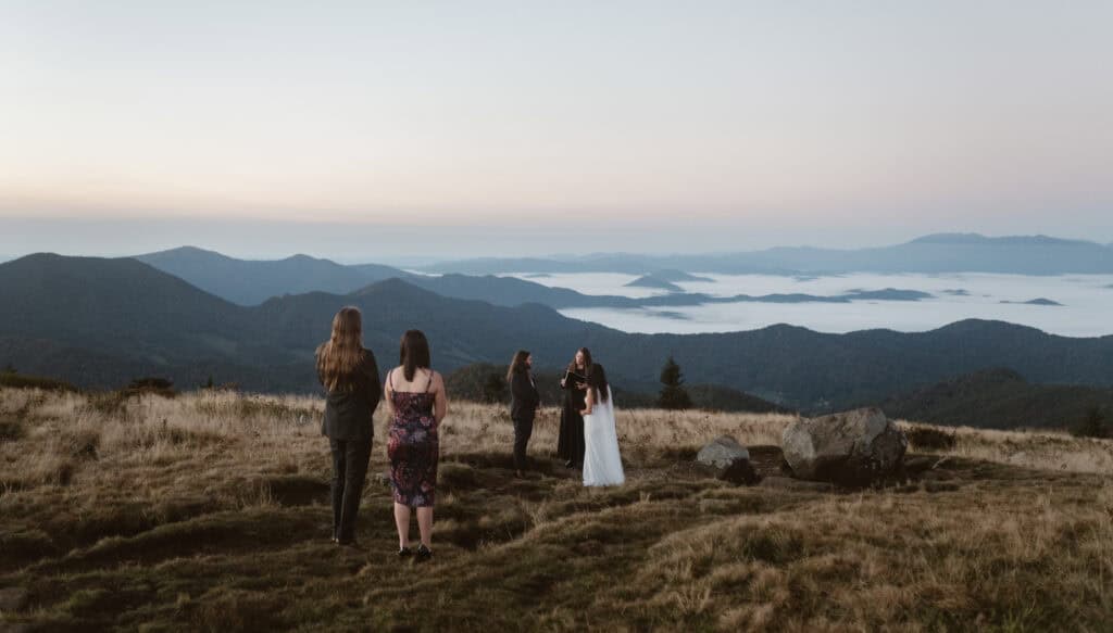 A bride and groom having their sunrise mountain hiking elopement ceremony with their loved-ones.