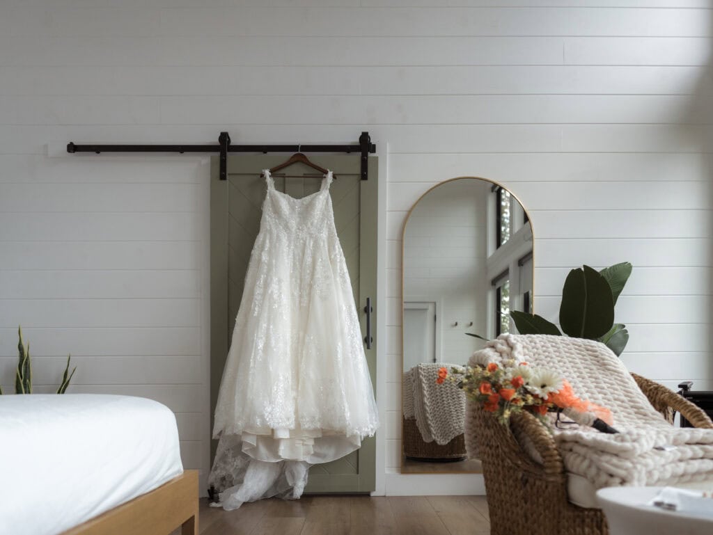 A wedding dress hanging on a door frame in a room. 