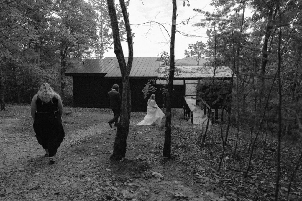 A newlywed couple and a family member walk to the entrance of their cabin rental. 