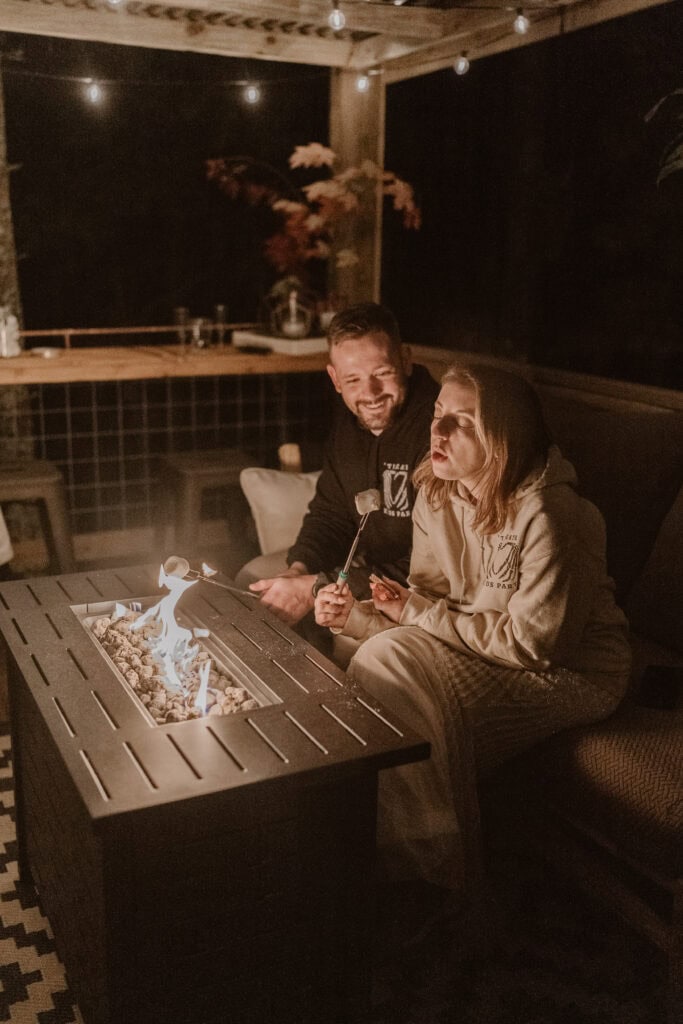 A newlywed couple enjoy making s'mores at their cabin rental. 