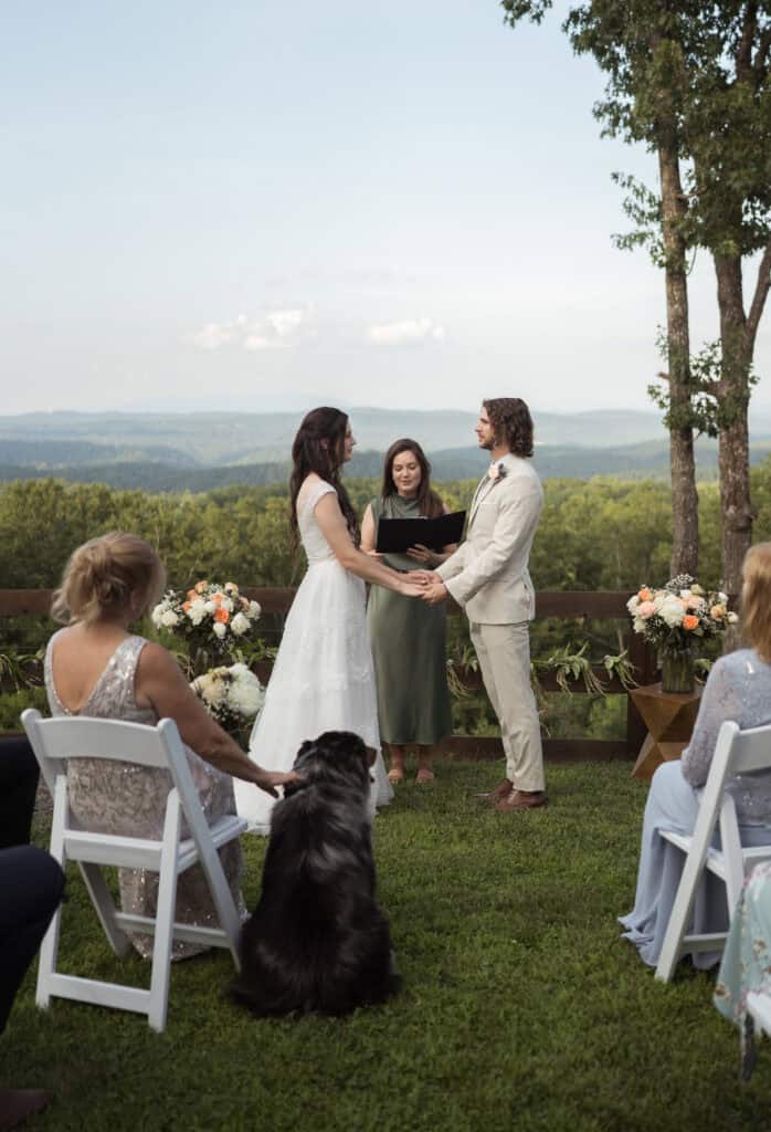 A couple holding hands and looking at each other with their family members sitting for their wedding ceremony. 