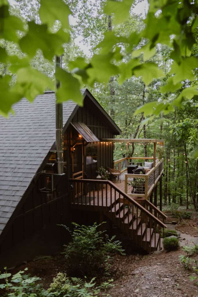 A view of a mountain cabin through leaves during the summer. 
