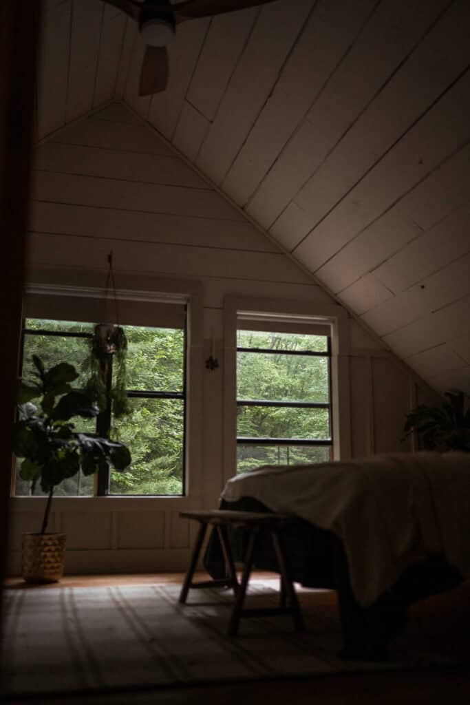 A view out into the forest while in a dimly lit bedroom. 