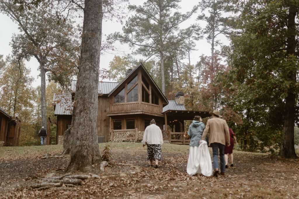 A newlywed couple walk on grass with their family members back to the inside of their Airbnb. 