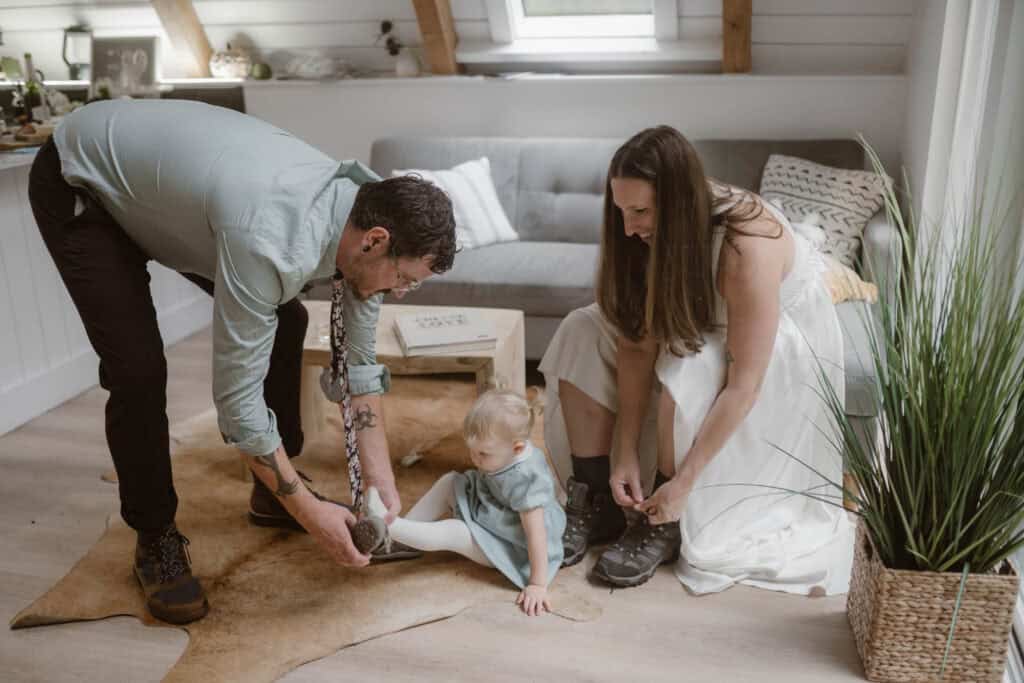 A couple getting ready into their wedding attire while helping their young child put their shoe on. 