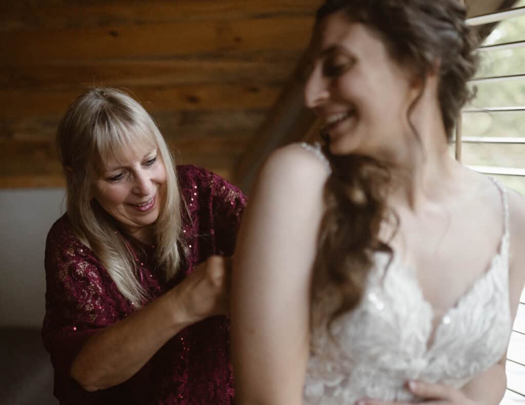 A mother helps her daughter into her wedding dress. 