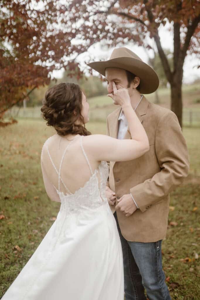 A couple experiences their first look in wedding attire and one partner wipes away the other partner's tear. 