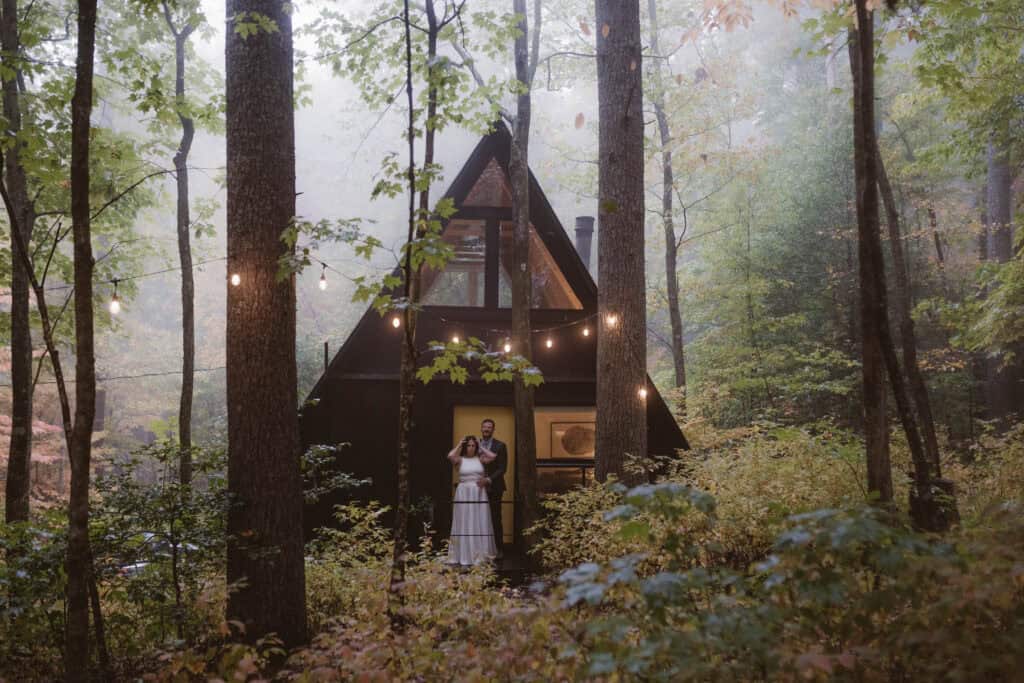 A newlywed couple standing in from of a yellow door to their vacation rental. 