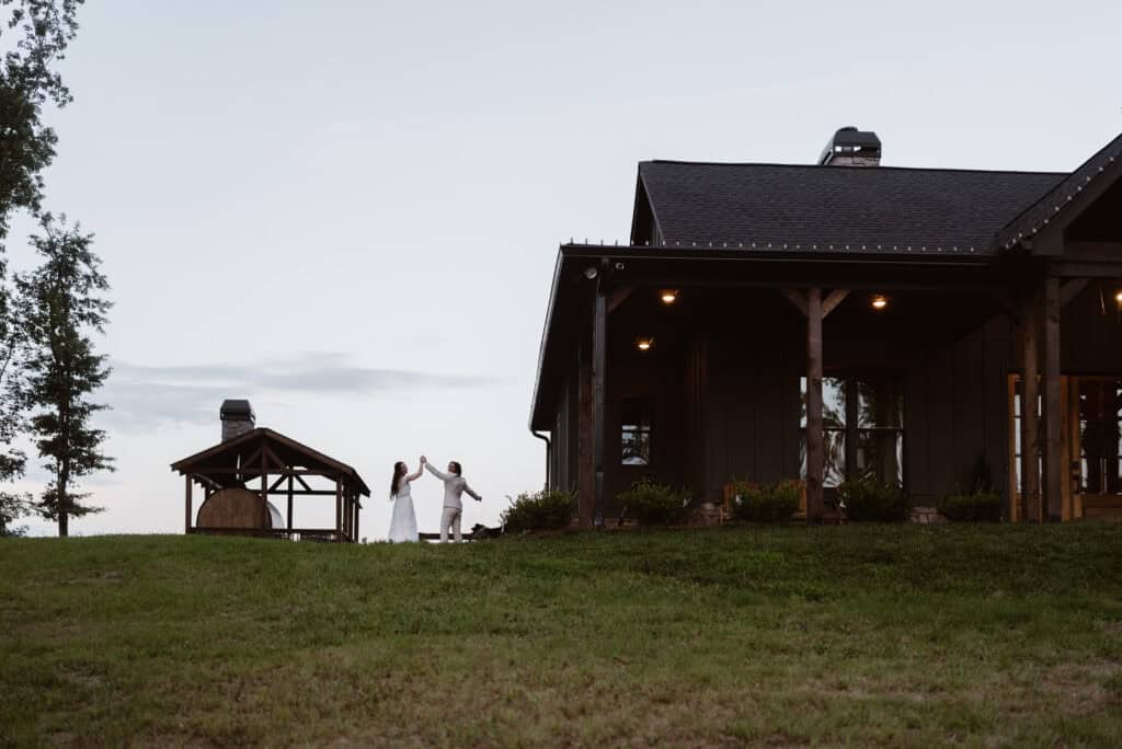 A newlywed couple throw their hands in the air in celebration while walking back into their cabin rental. 